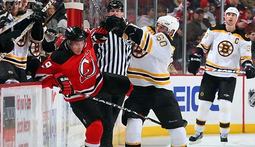 Devils-Star Zach Parise (l.) wird im Spiel gegen Boston in die Bande gecheckt