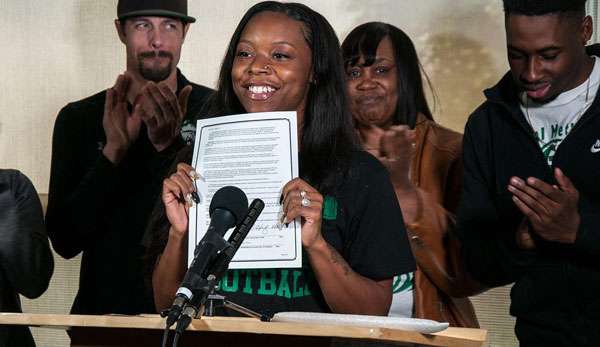 Toni Harris zeigt Stolz ihren Letter of Intent, der ihr ein College-Football-Stipendium zusichert.