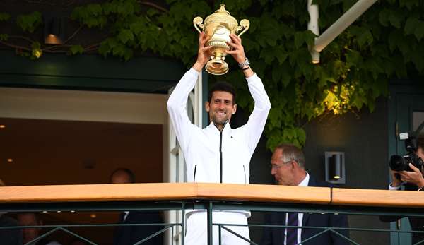Novak Djokovic präsentiert seinen Pokal auf dem berühmten Südbalkon von Wimbledon.