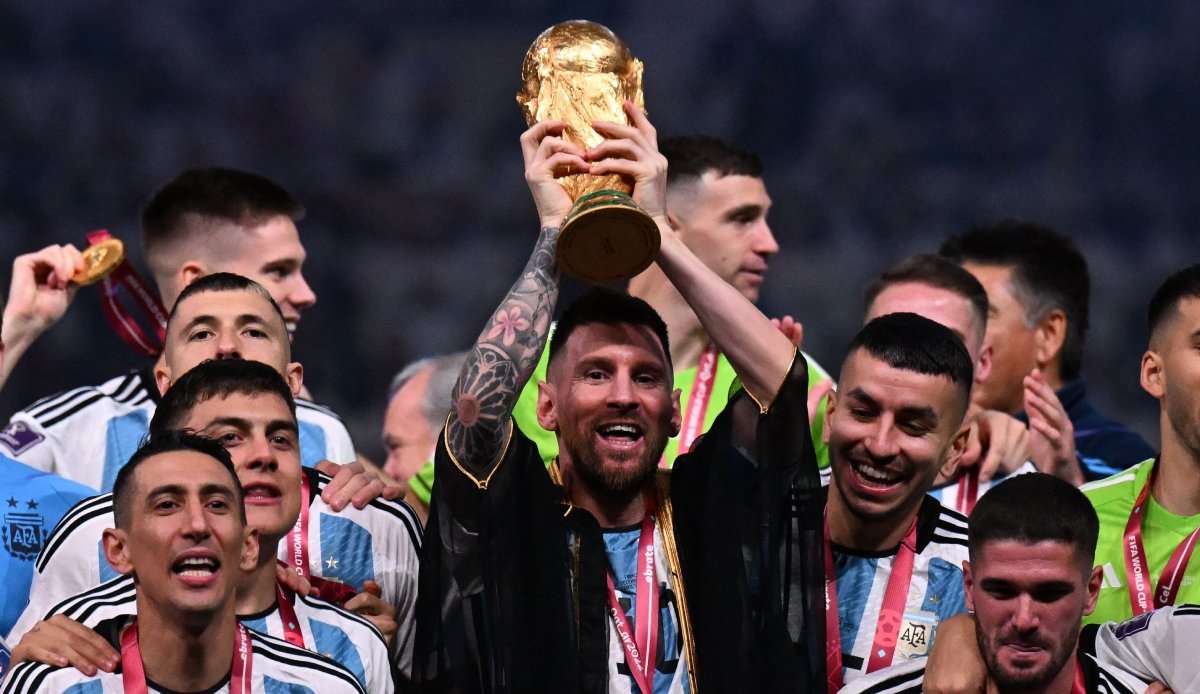 Lionel Messi reckt den WM-Pokal in die Höhe - mit einem Bisht über dem Nationaltrikot.