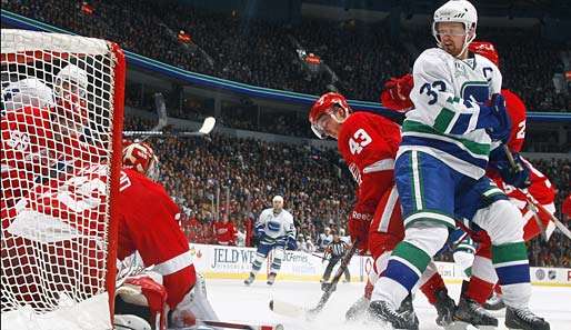 Vancouvers Henrik Sedin (r.) spekuliert gegen Jimmy Howard (l.) auf den Rebound